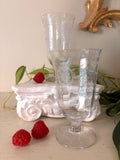 Two matching clear glass footed tumblers etched with a floral and scroll band below the rim.