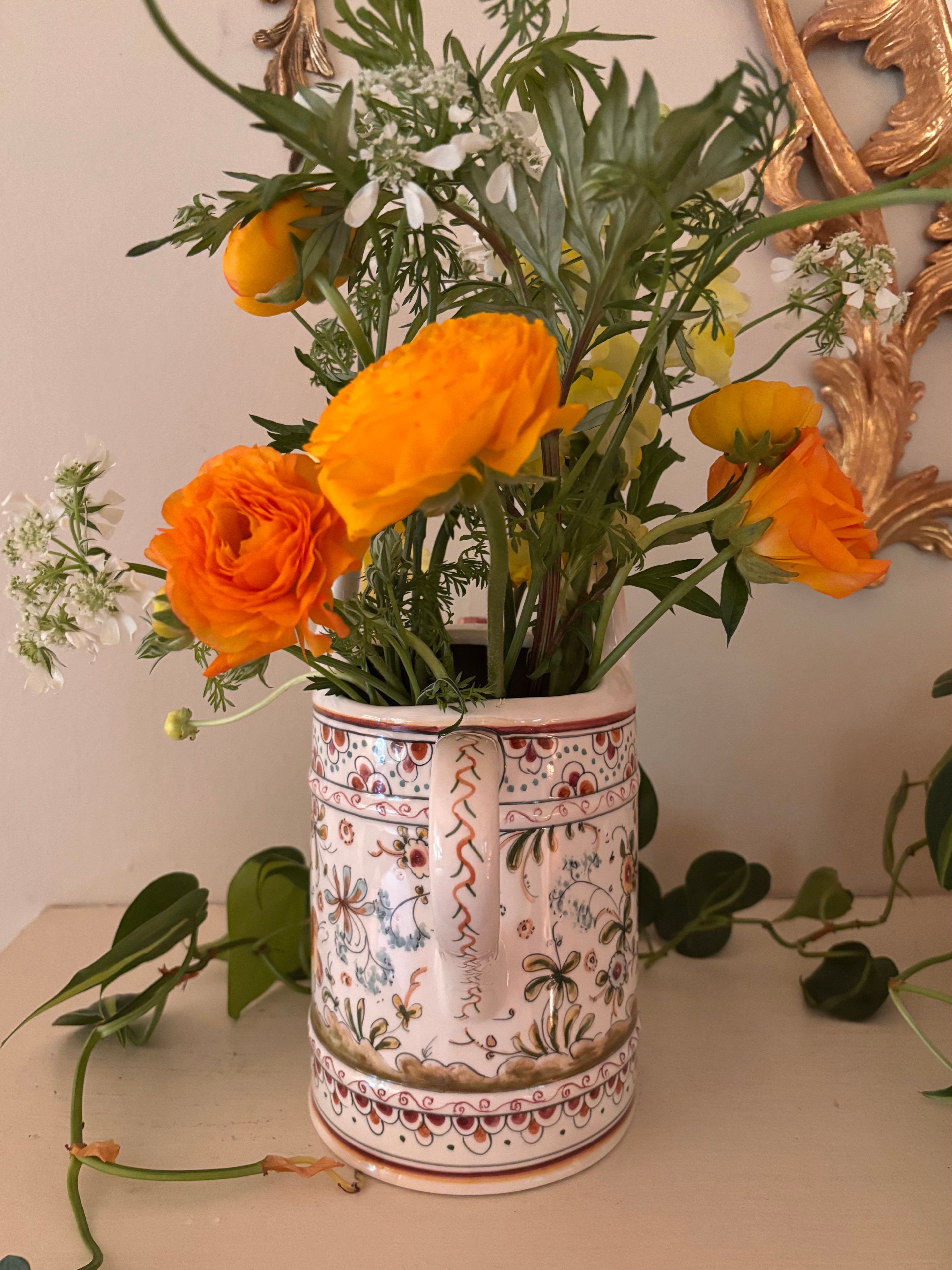 Back view of hand-painted ceramic watering can showing loop handle and folk art botanical motifs on cream ground.
