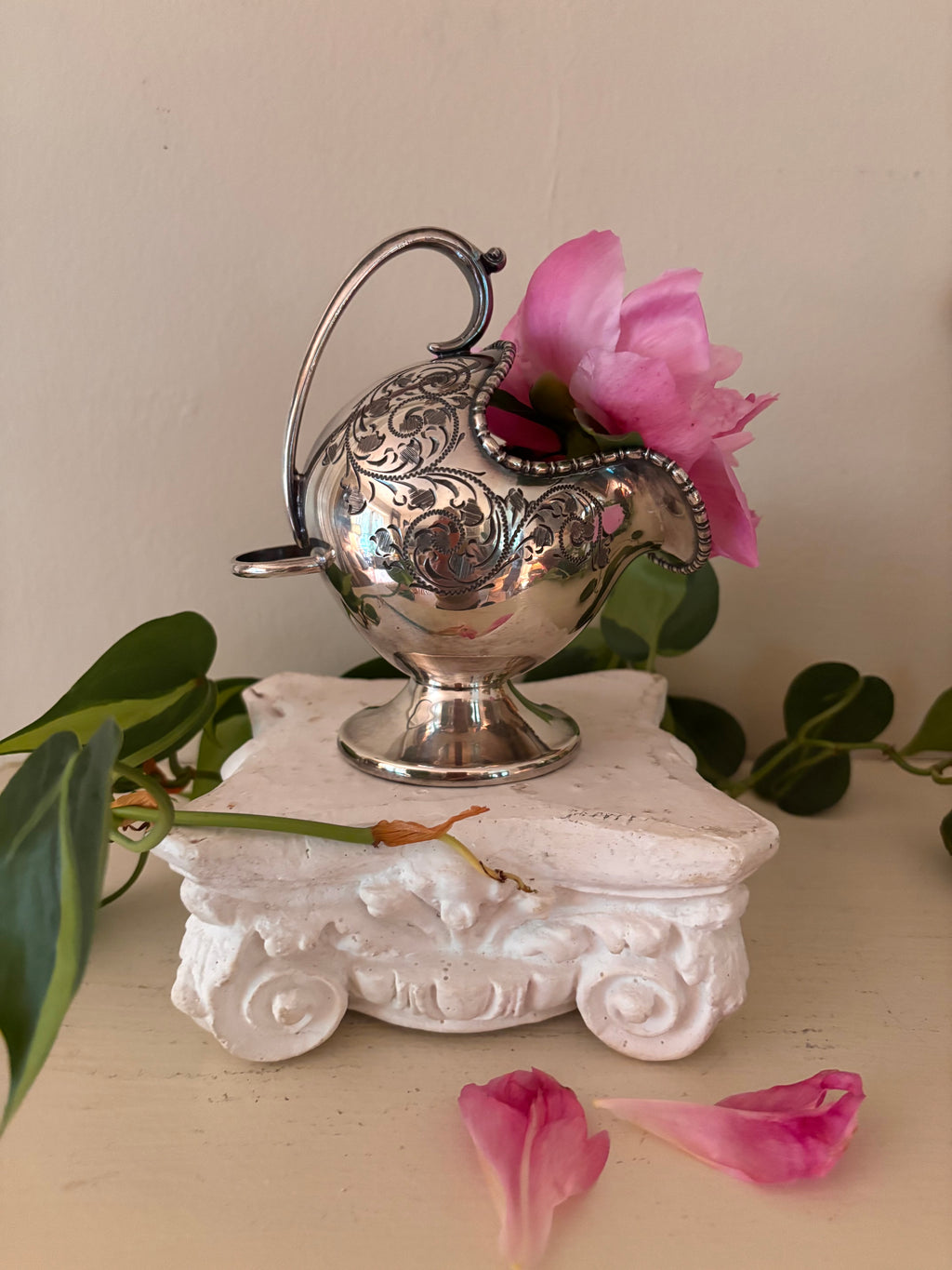 Side view of engraved silver-plate sugar scuttle showing small side tab and acanthus scroll detail on body.