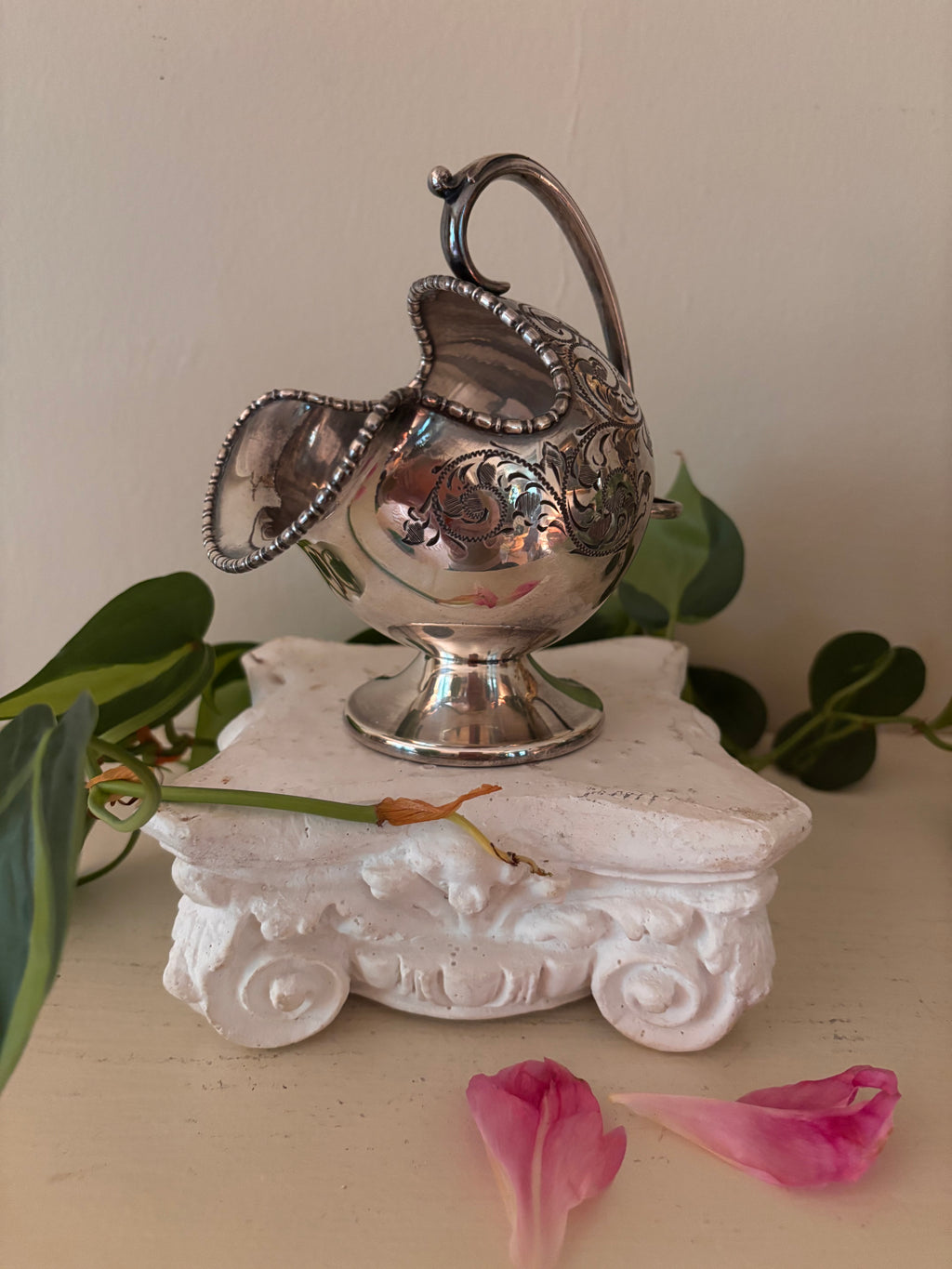 Tilted view of silver-plate sugar scuttle showing angled opening with beaded border and engraved body.