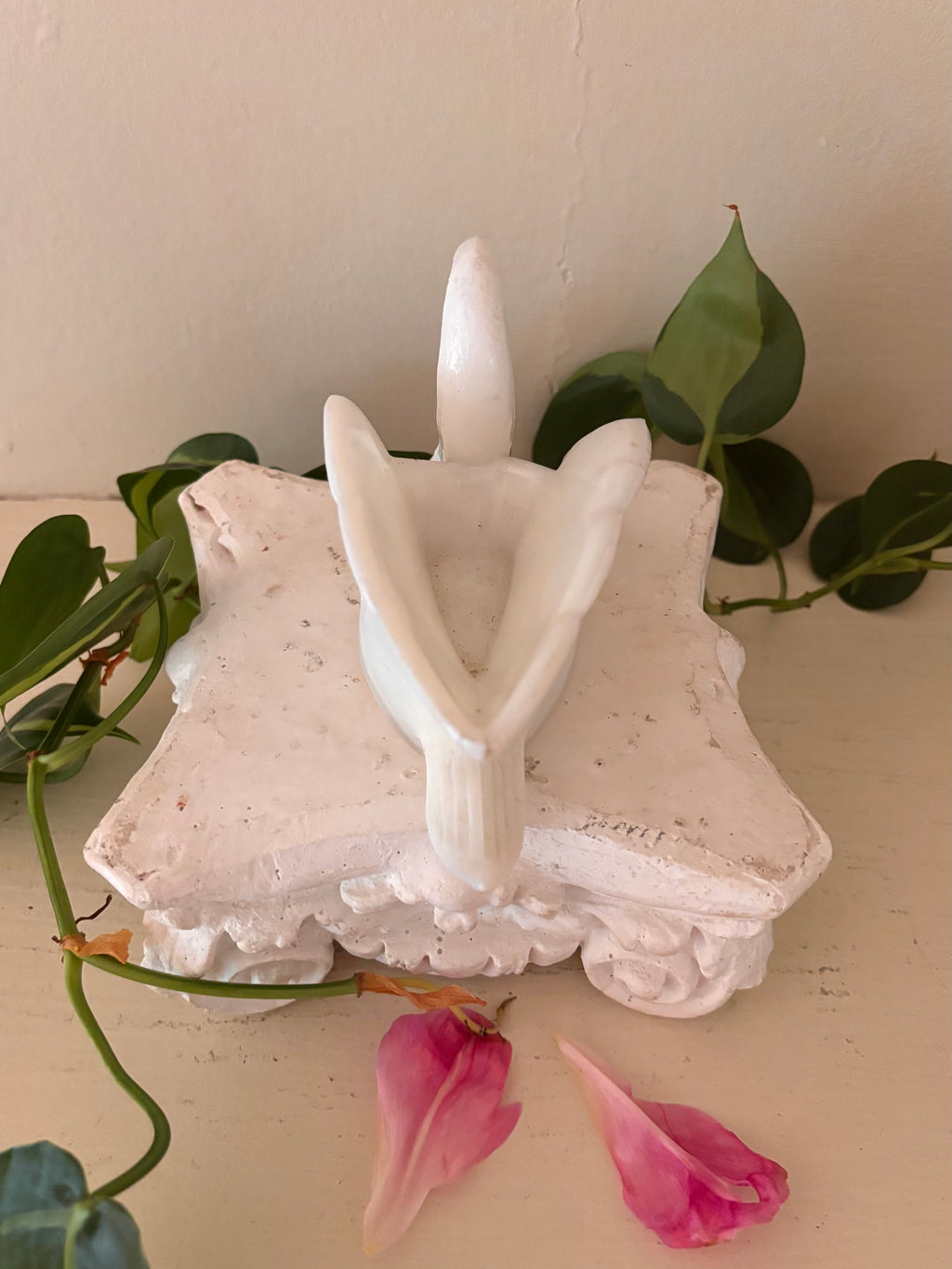 Rear view of white porcelain swan showing upright tail and folded wing form.