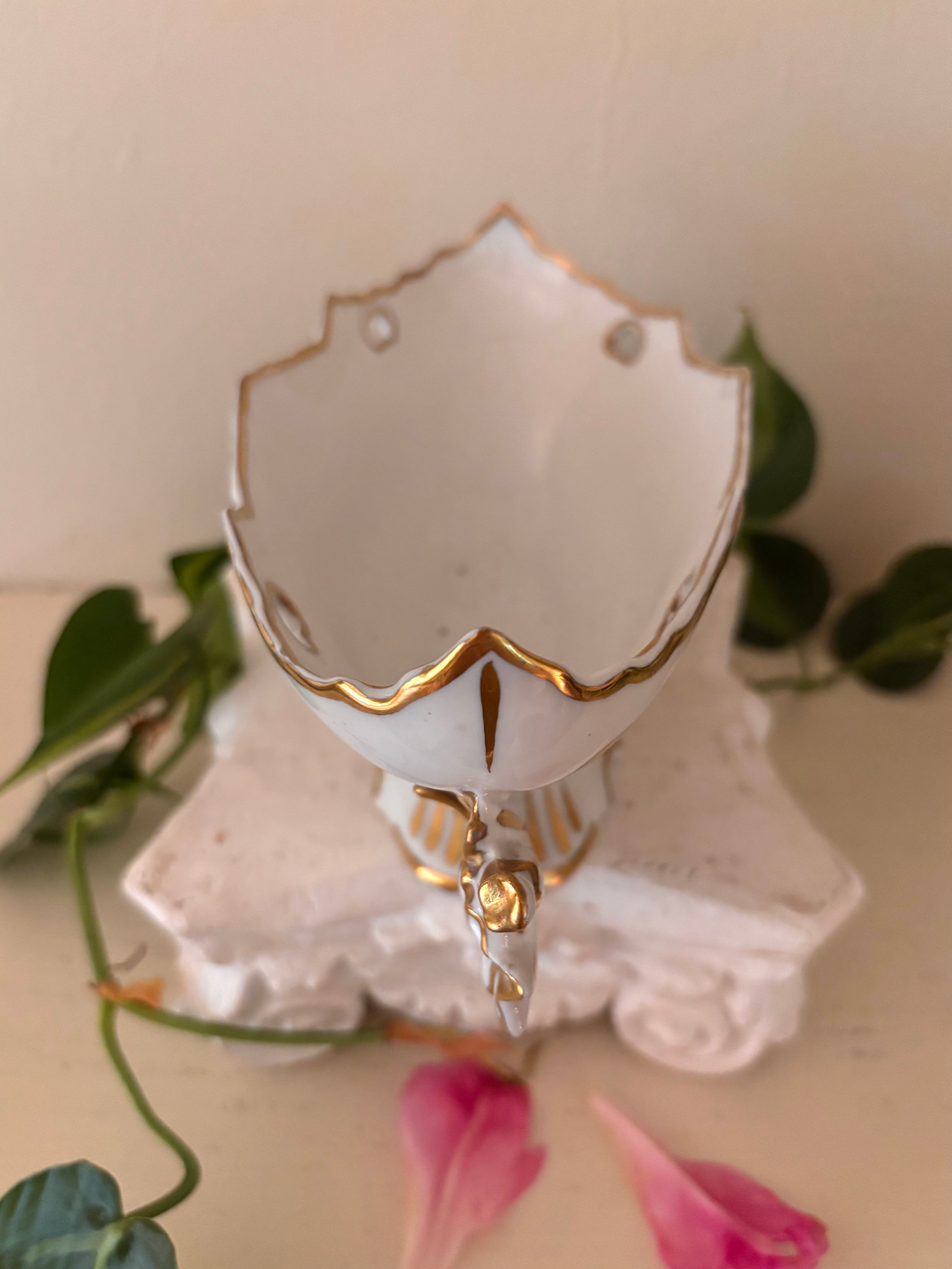 Overhead interior view of white porcelain centerpiece bowl with gilt rim and painted base detail.