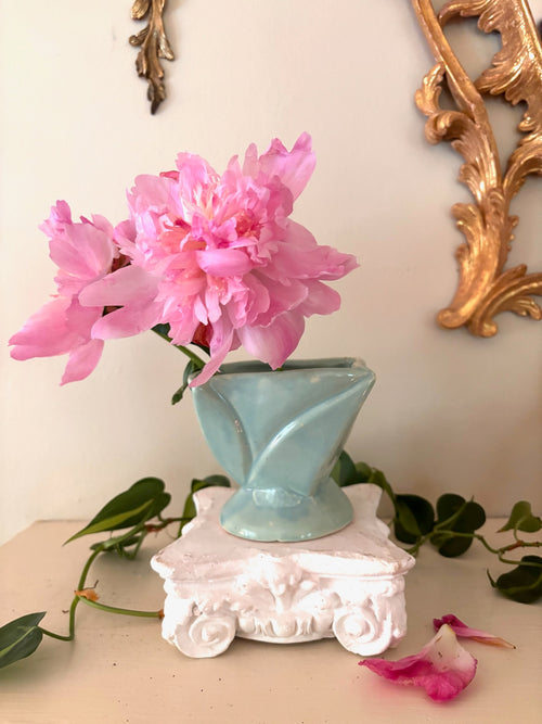 Pale mint glossy ceramic footed vase with angular faceted body and round pedestal base.