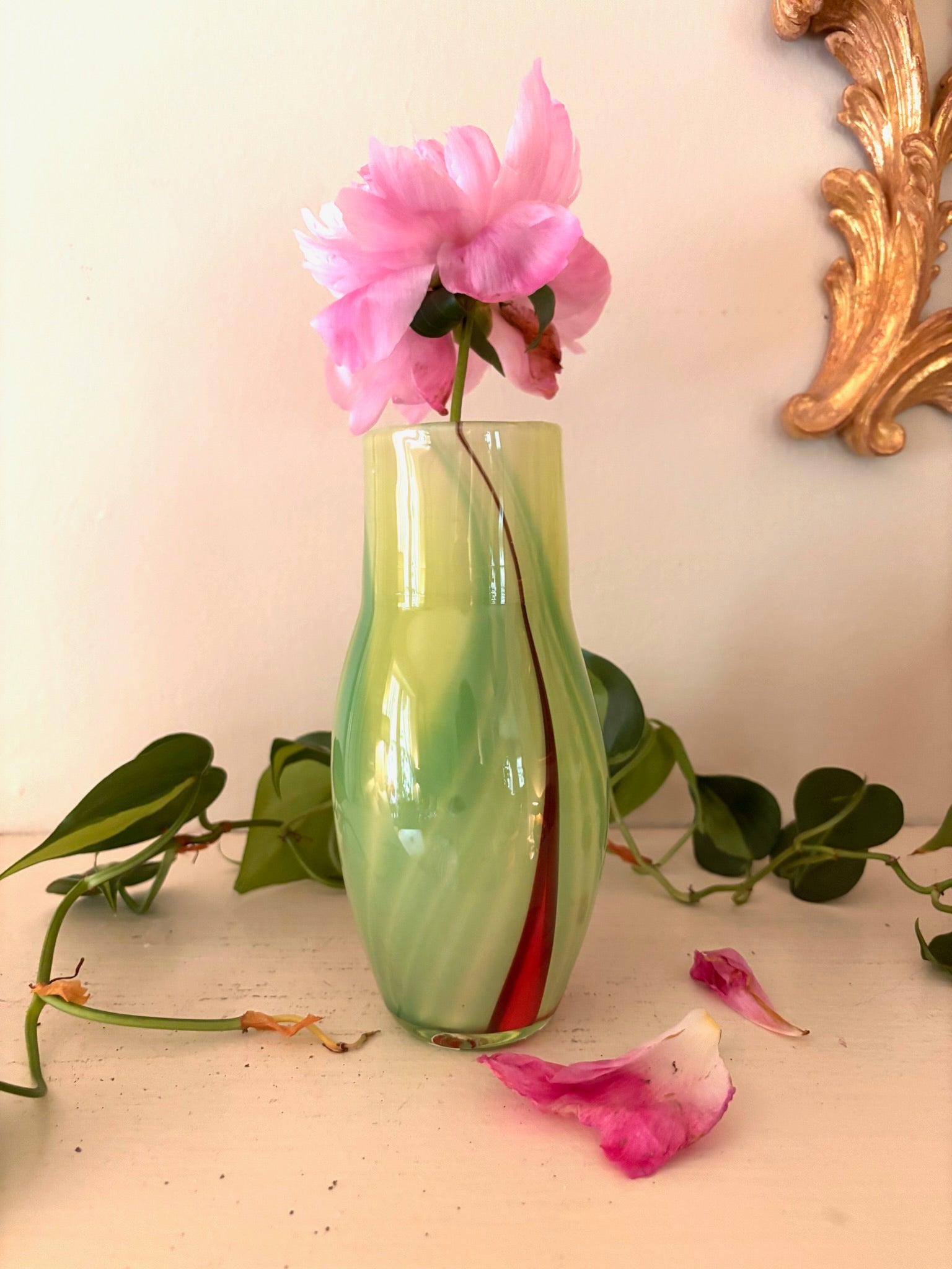 Hand-blown chartreuse green art glass vase with diagonal crimson swirl, curved organic form.