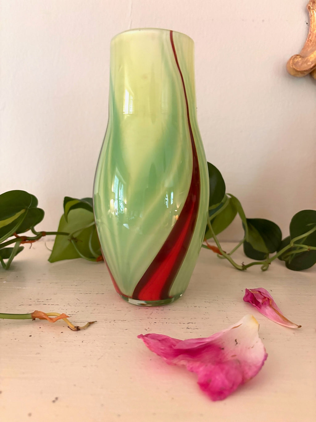 Hand-blown chartreuse green art glass vase with diagonal crimson swirl, curved organic form.