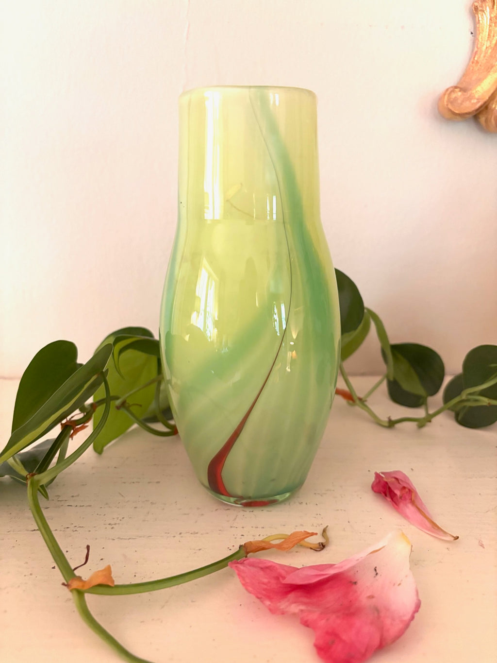 Hand-blown chartreuse green art glass vase with diagonal crimson swirl, curved organic form.