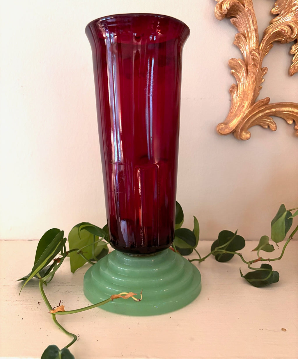 Tall ruby red ribbed glass vase seated on a stepped jade green ceramic pedestal base.