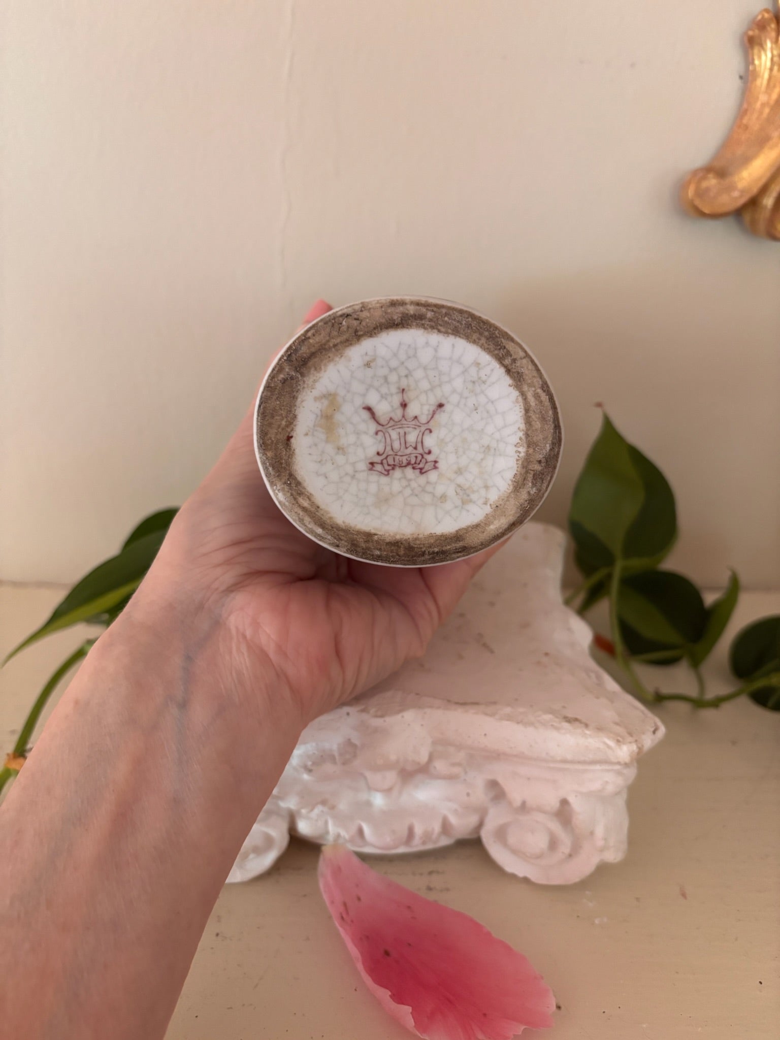 Base of antique porcelain vase showing crown maker's mark with initials and crazing on unglazed foot.