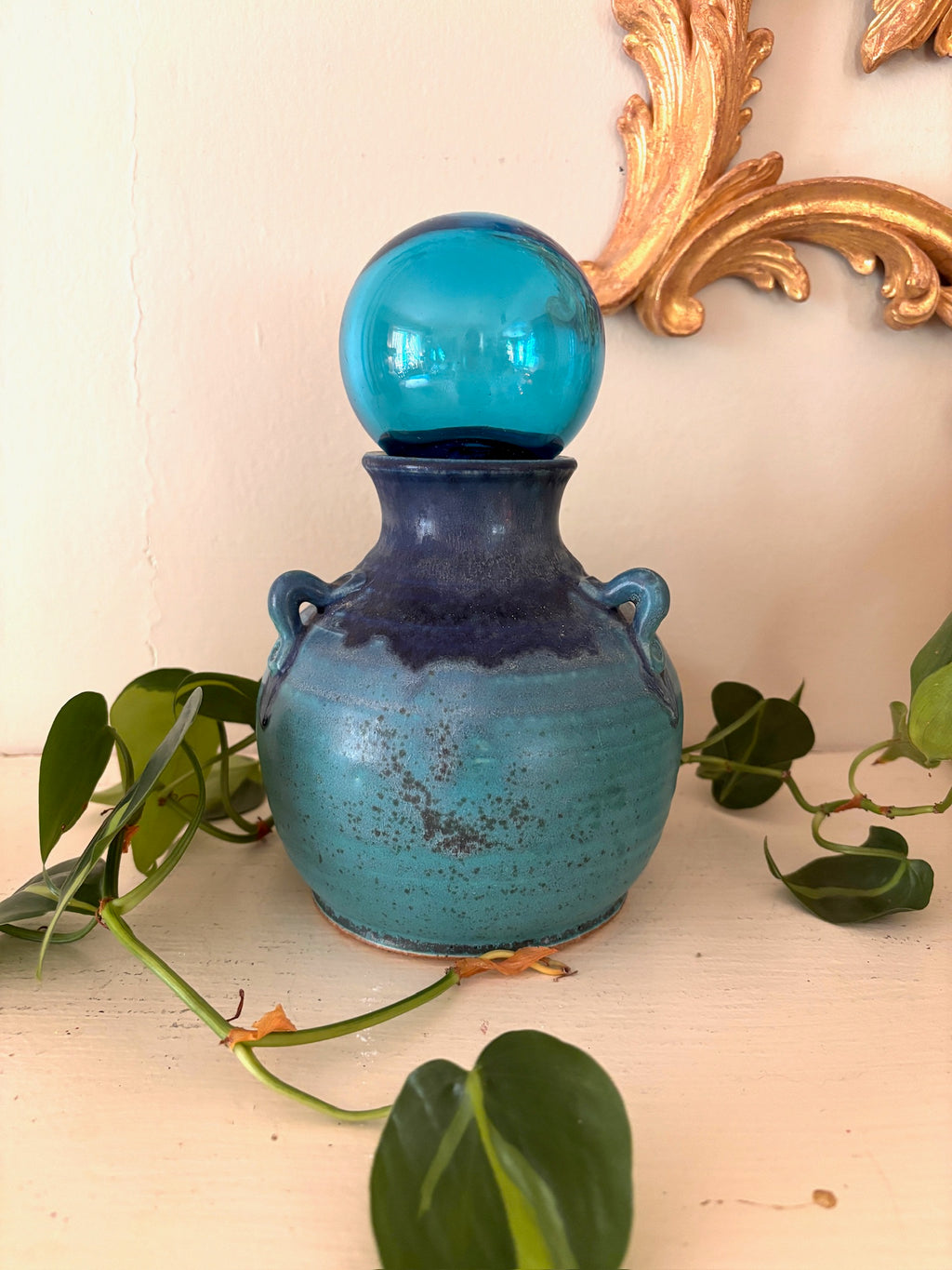 Round studio pottery vase with teal to indigo reactive glaze and small loop handles.