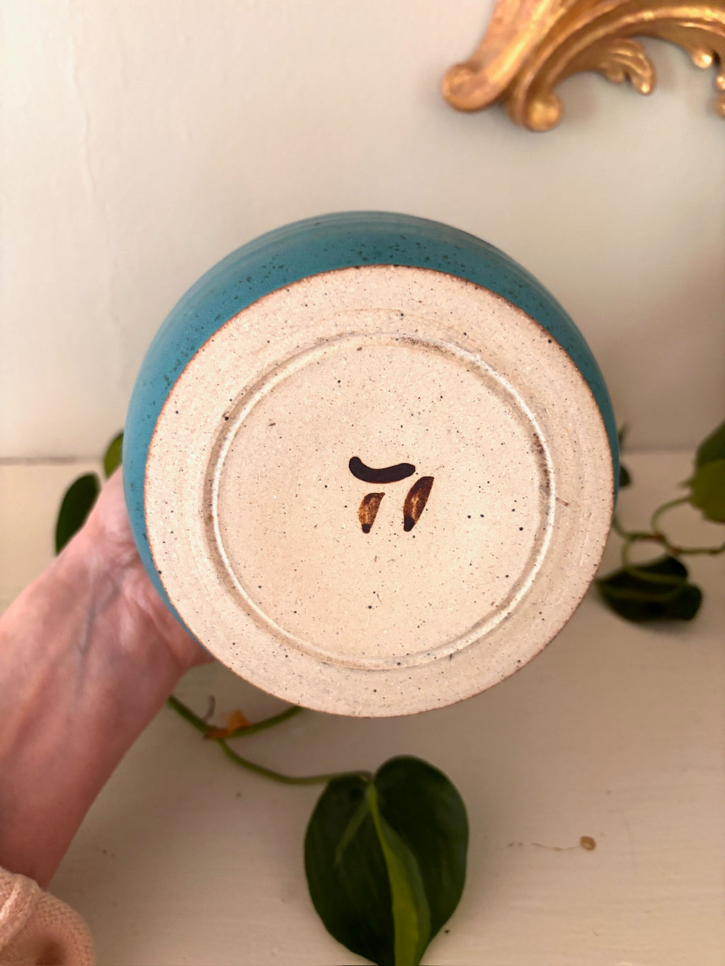 Base of teal studio pottery vase showing small incised maker's mark.