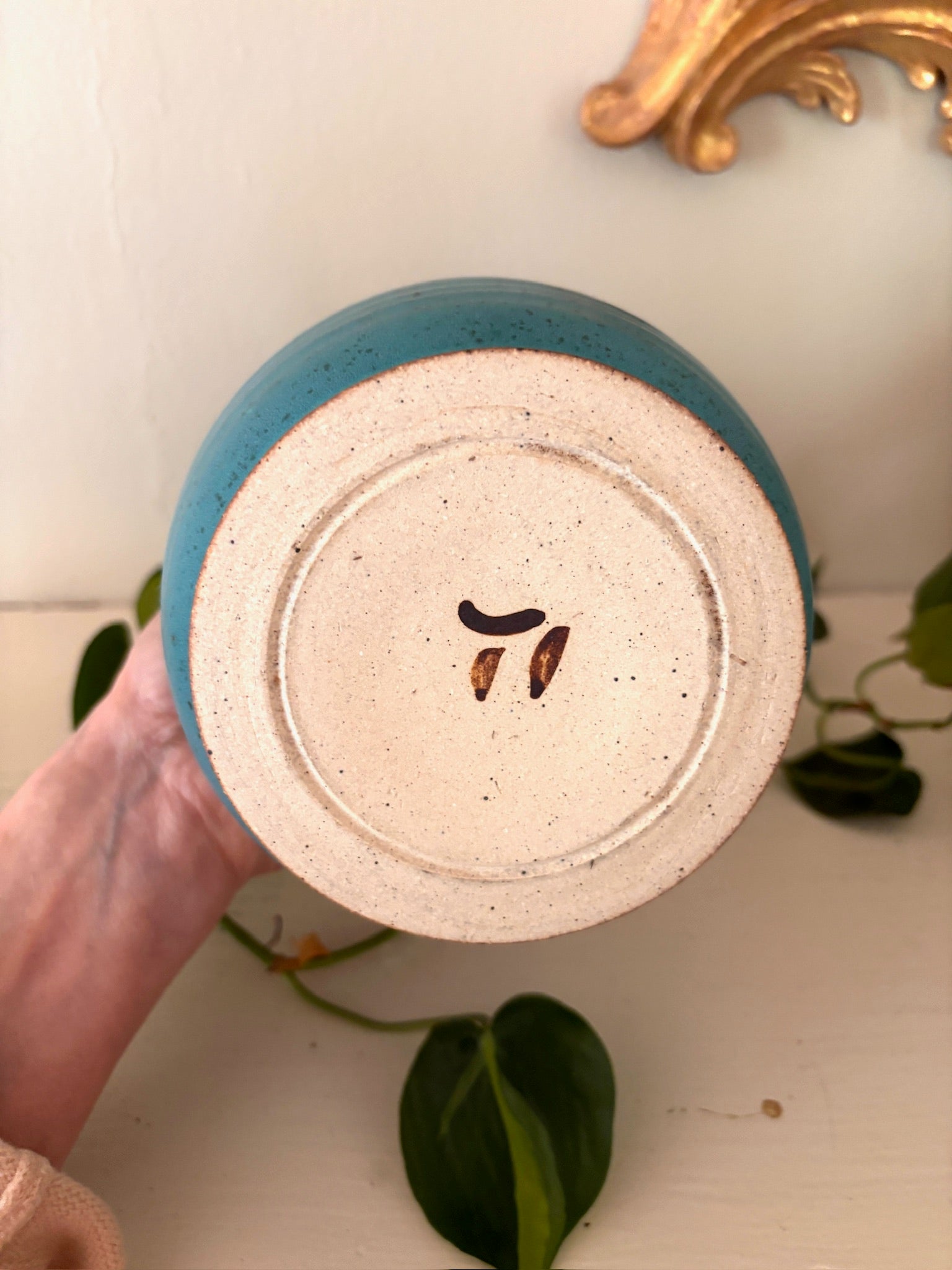Base of teal studio pottery vase showing small incised maker's mark.