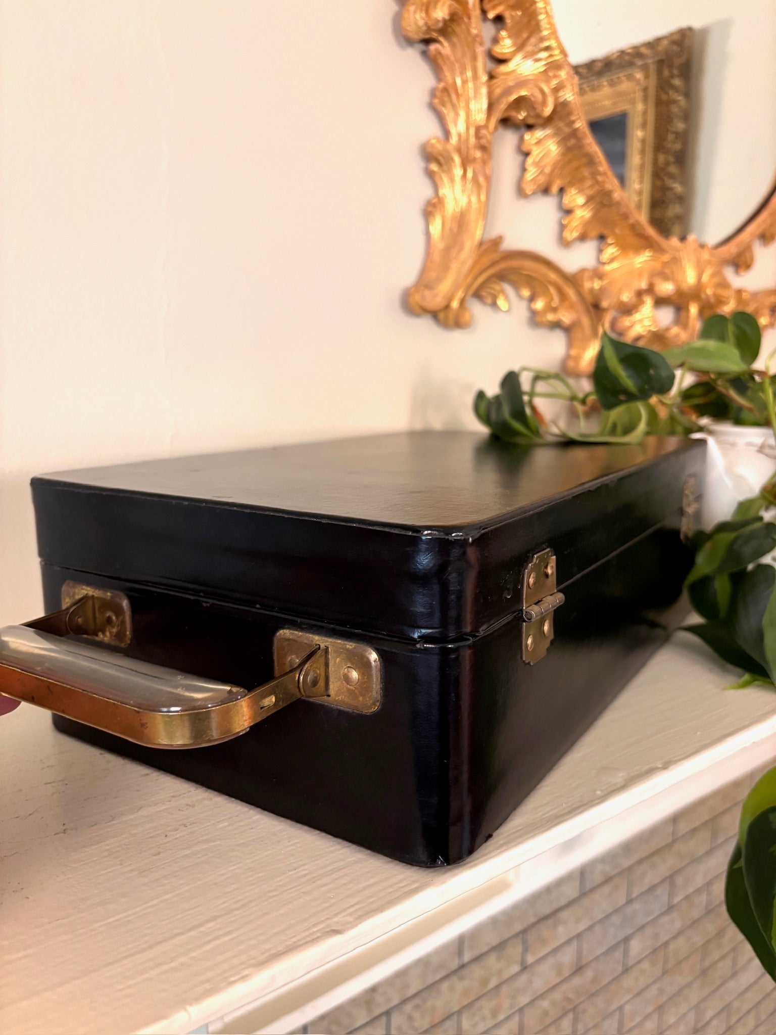Black travel bar case standing upright with brass swing handle and front brass latch.
