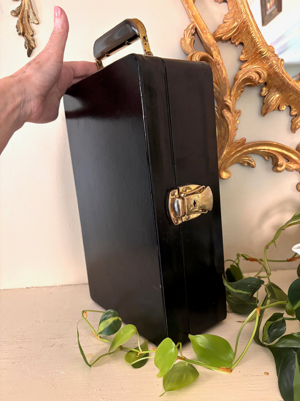 Closed black travel bar case with brass swing handle, hinges, and side latches.