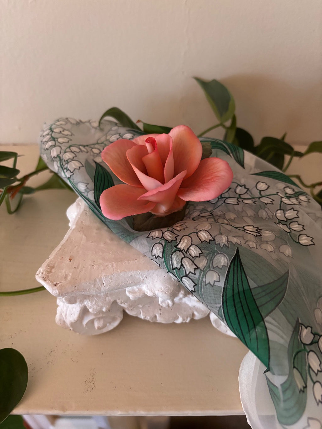 Hand-crafted decorative porcelain rose sculpture in coral and salmon pink with layered petals and dark stem base