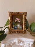 Miniature impressionist floral oil painting depicting pink blooms and small vases in loose expressive brushwork, set in an ornate carved gilt Florentine frame with pierced scrollwork corners