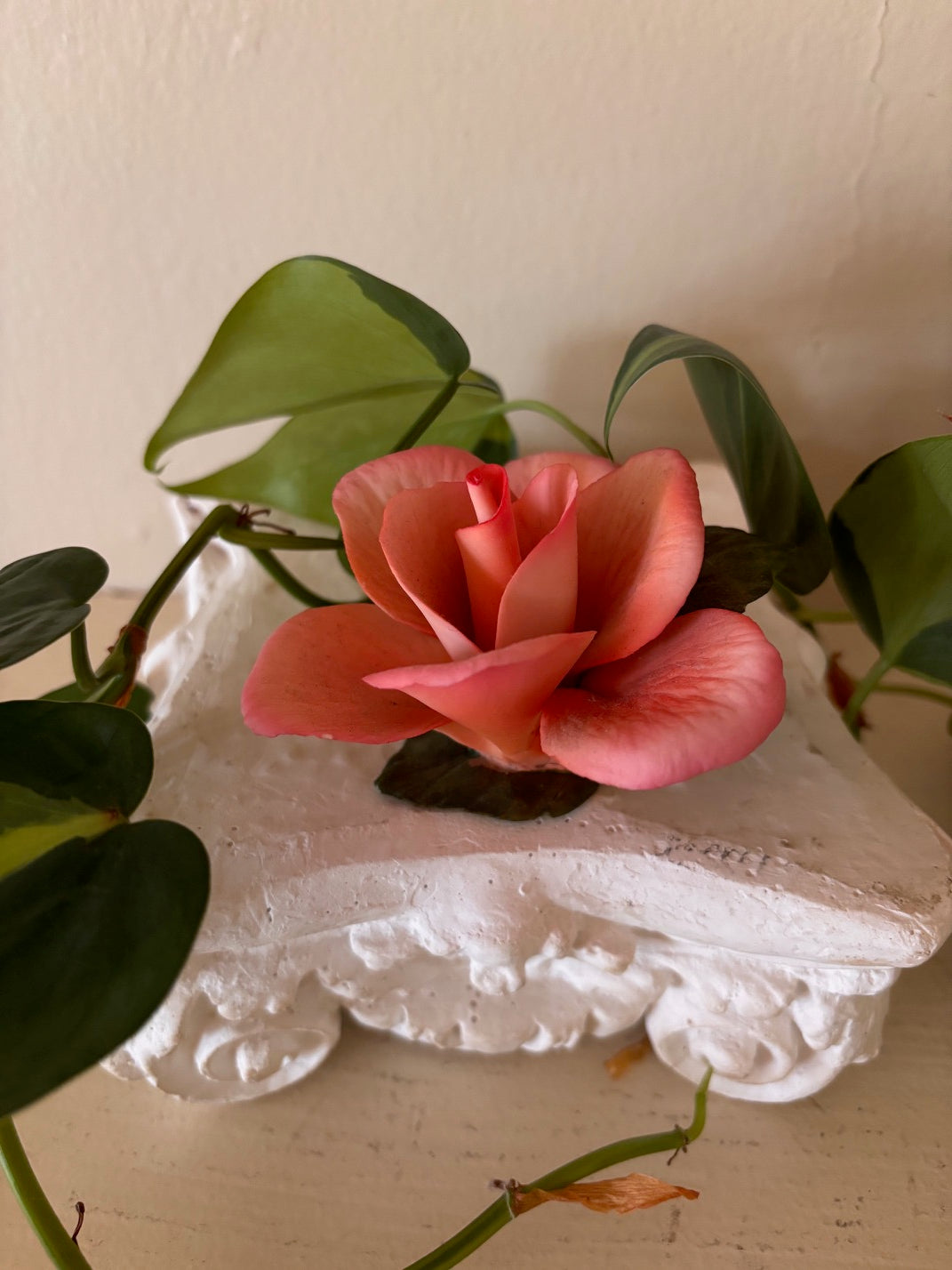 Hand-crafted decorative porcelain rose sculpture in coral and salmon pink with layered petals and dark stem base