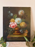 Signed oil painting floral still life in Dutch Golden Age style depicting a lush mixed bouquet with pink peony, white and yellow chrysanthemums, and blue flowers in a golden urn on a dark background, signed lower left in red