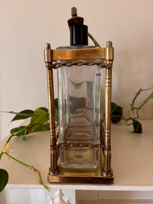 Side view - Antique brass tantalus liquor caddy with three glass decanters stenciled in gold with spirit names including Gin and Scotch, with twisted rope rail detailing, turned corner columns, and Bakelite stoppers