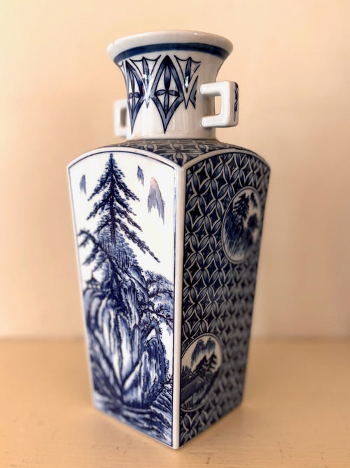 Square blue and white porcelain vase with twin handles, a landscape panel of pine and mountains, and lattice sides.