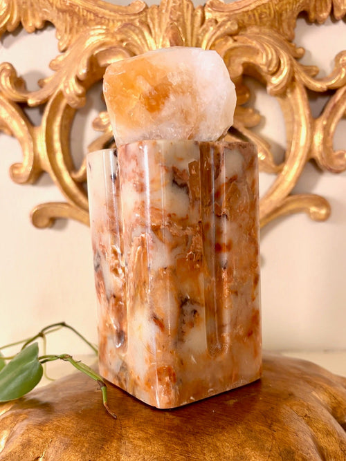 Close view of a carved stone pillar vase showing rust and cream veining.