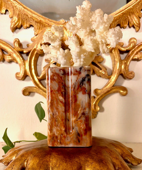 Carved stone pillar vase with rust-orange veining and faceted sides.
