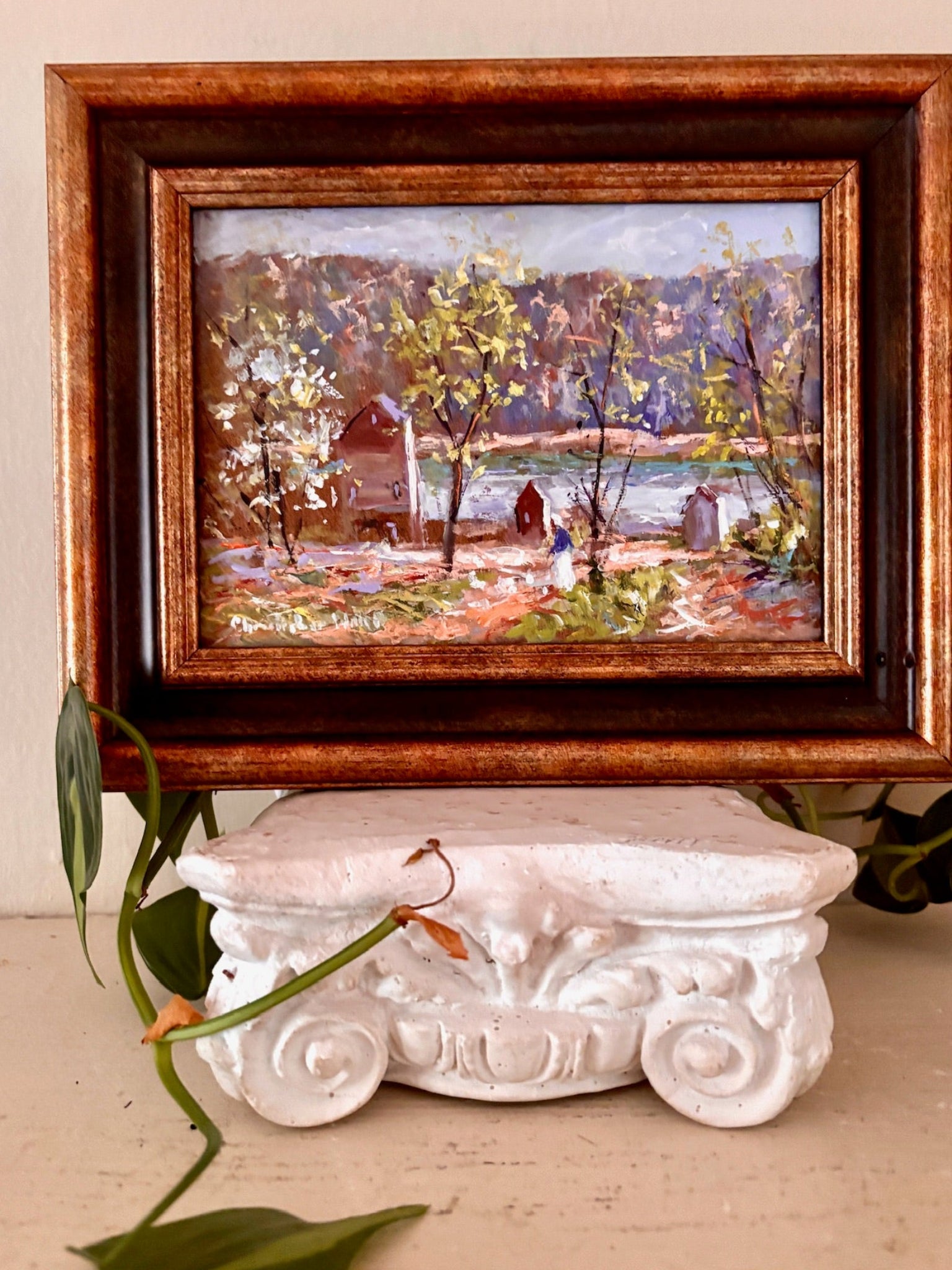 Small oil landscape painting of a red barn and pond framed by autumn trees, in a bronze wood frame.