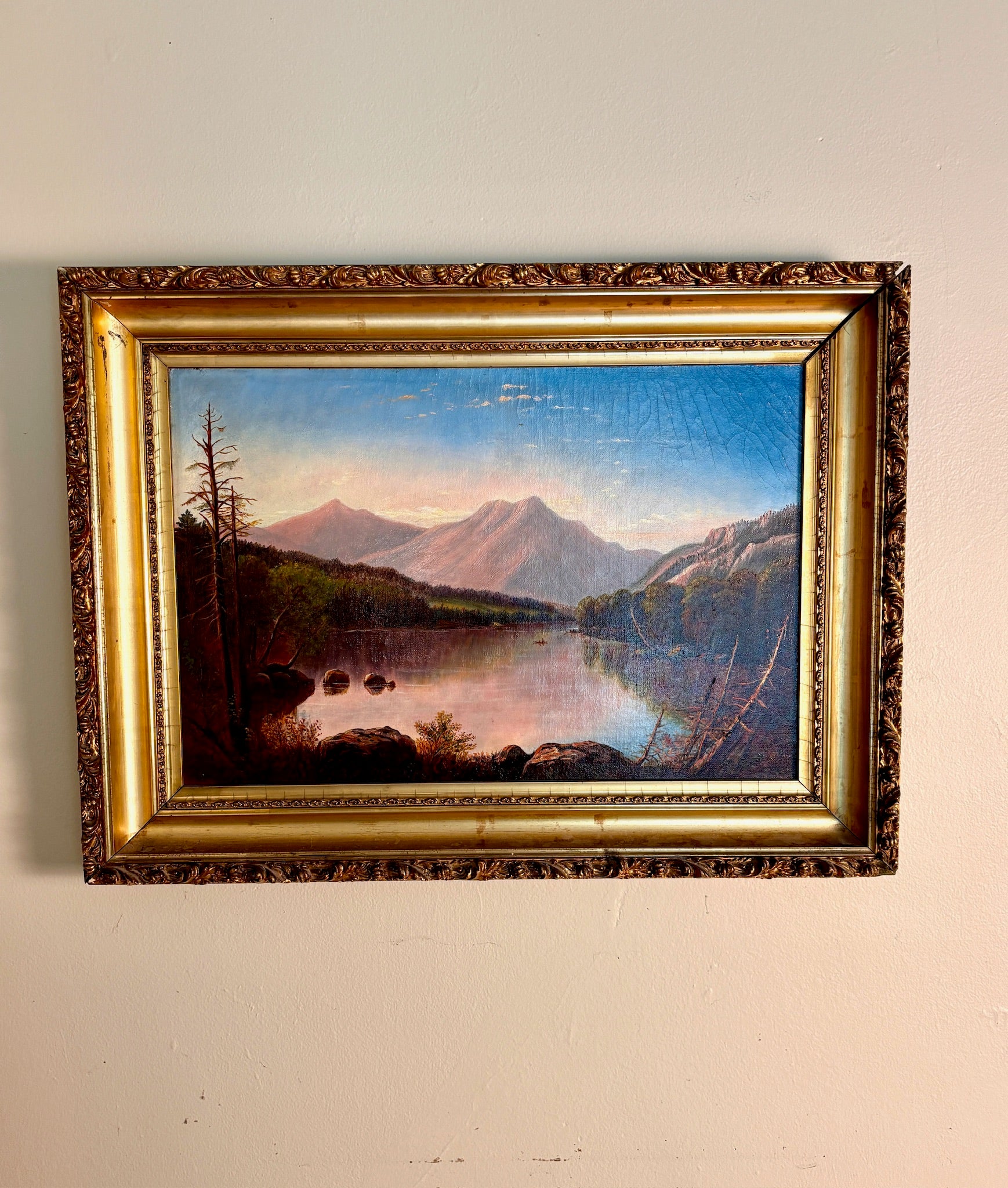 Framed oil painting of a mountain lake landscape at dusk in an ornate gilt frame.