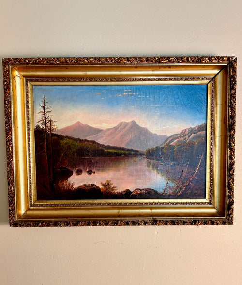 Framed oil painting of a mountain lake landscape at dusk in an ornate gilt frame.