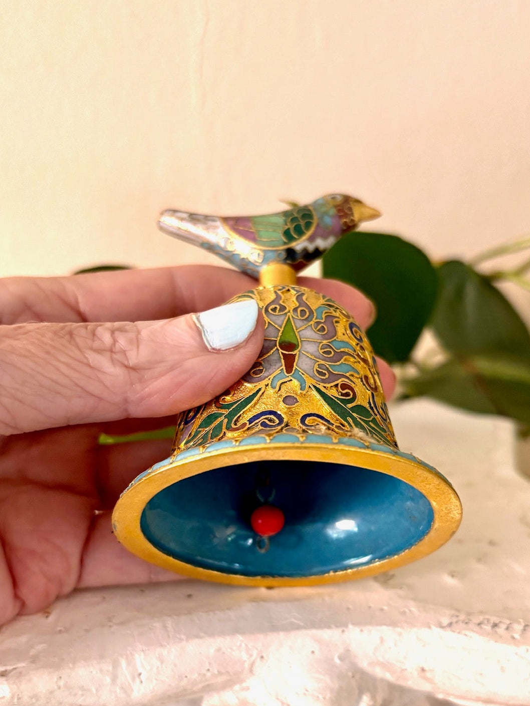 Interior view of gilt cloisonné enamel bell showing teal enamel and red bead clapper.