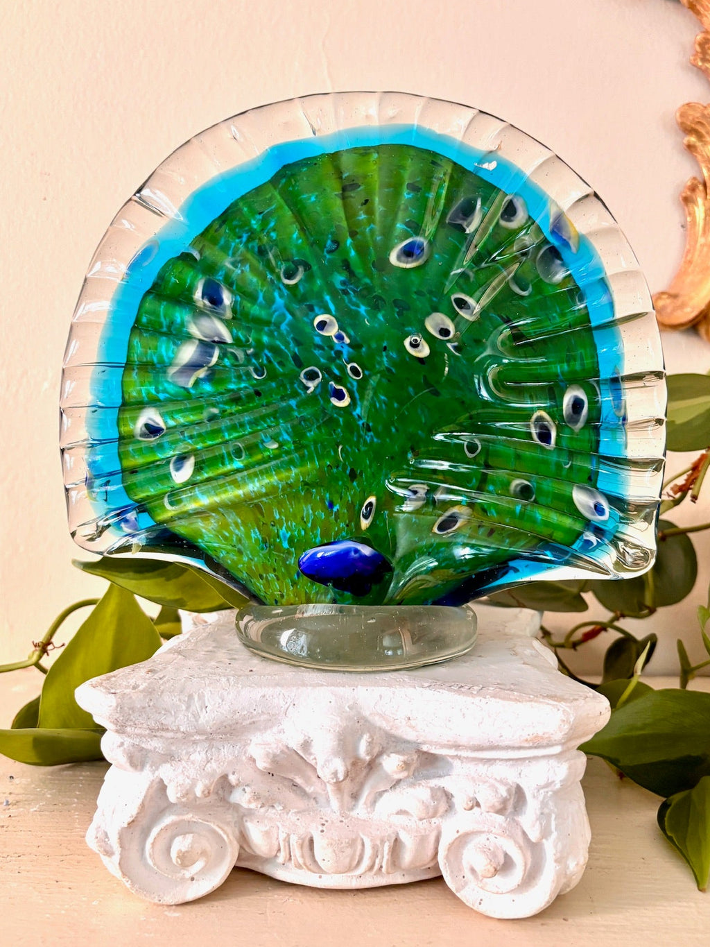 Back view of hand-blown glass peacock figurine on a clear glass footed base.