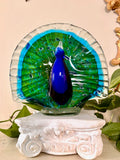 Hand-blown glass peacock figurine with emerald and turquoise fanned tail and cobalt blue body.