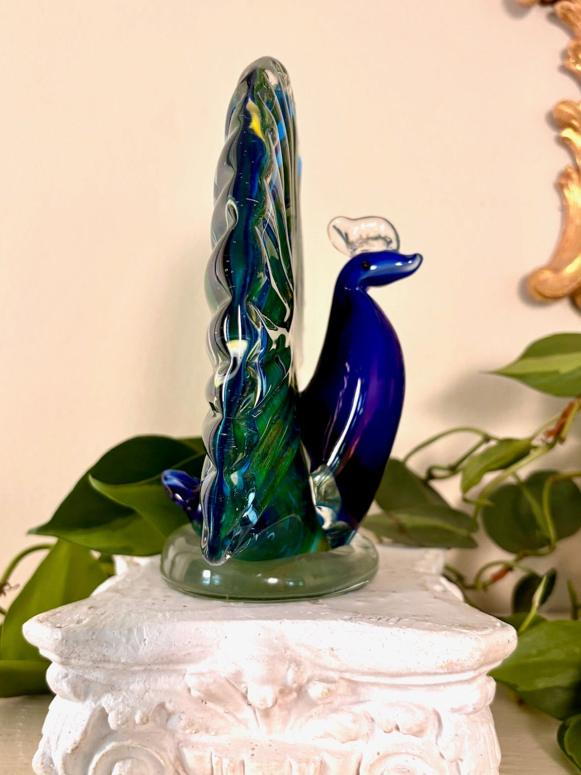 Side view of hand-blown glass peacock figurine showing cobalt blue neck and head.