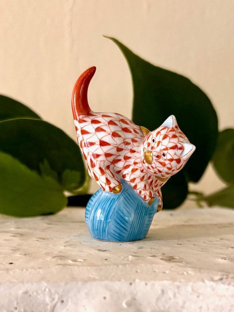 Herend Rust fishnet pattern porcelain cat figurine perched on a blue ball of yarn with gold accents.