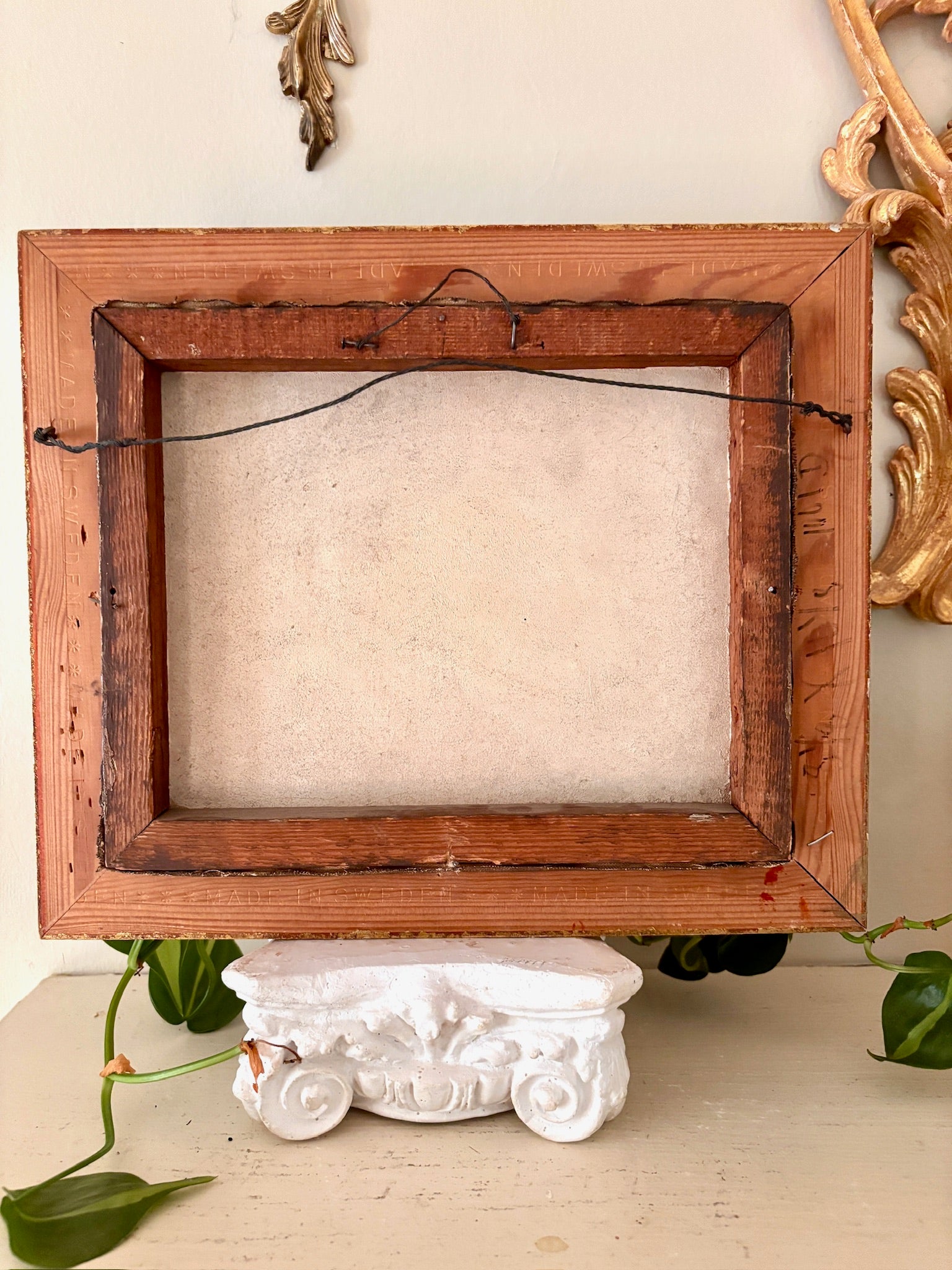 Back of a gilt picture frame stamped "Made in Sweden" along the wood edge.