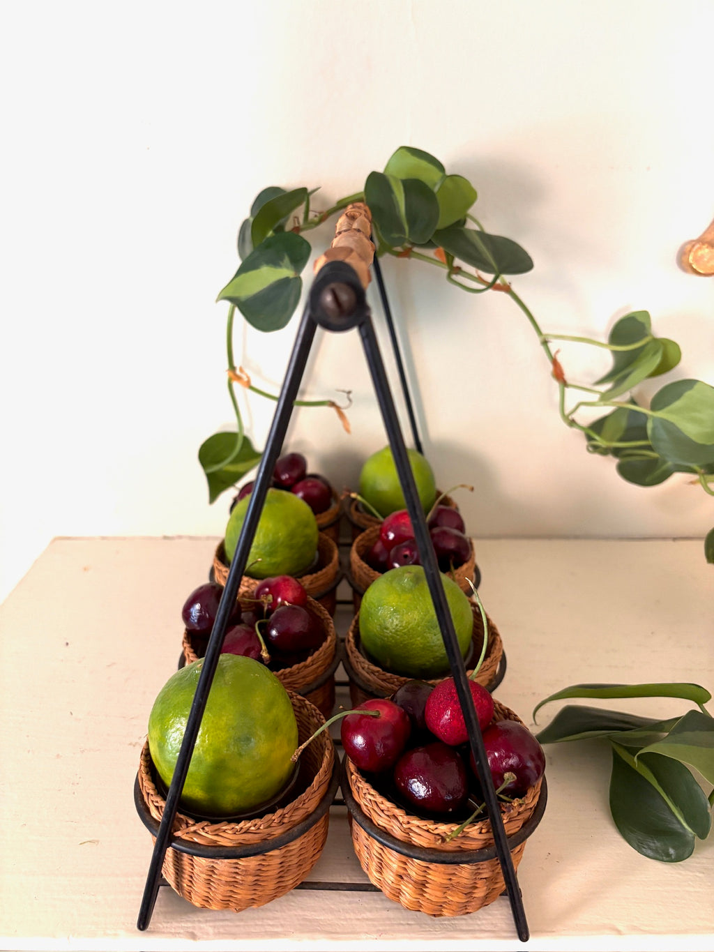 Top view of the rattan basket caddy showing the black A-frame handle meeting at a bamboo-wrapped grip.