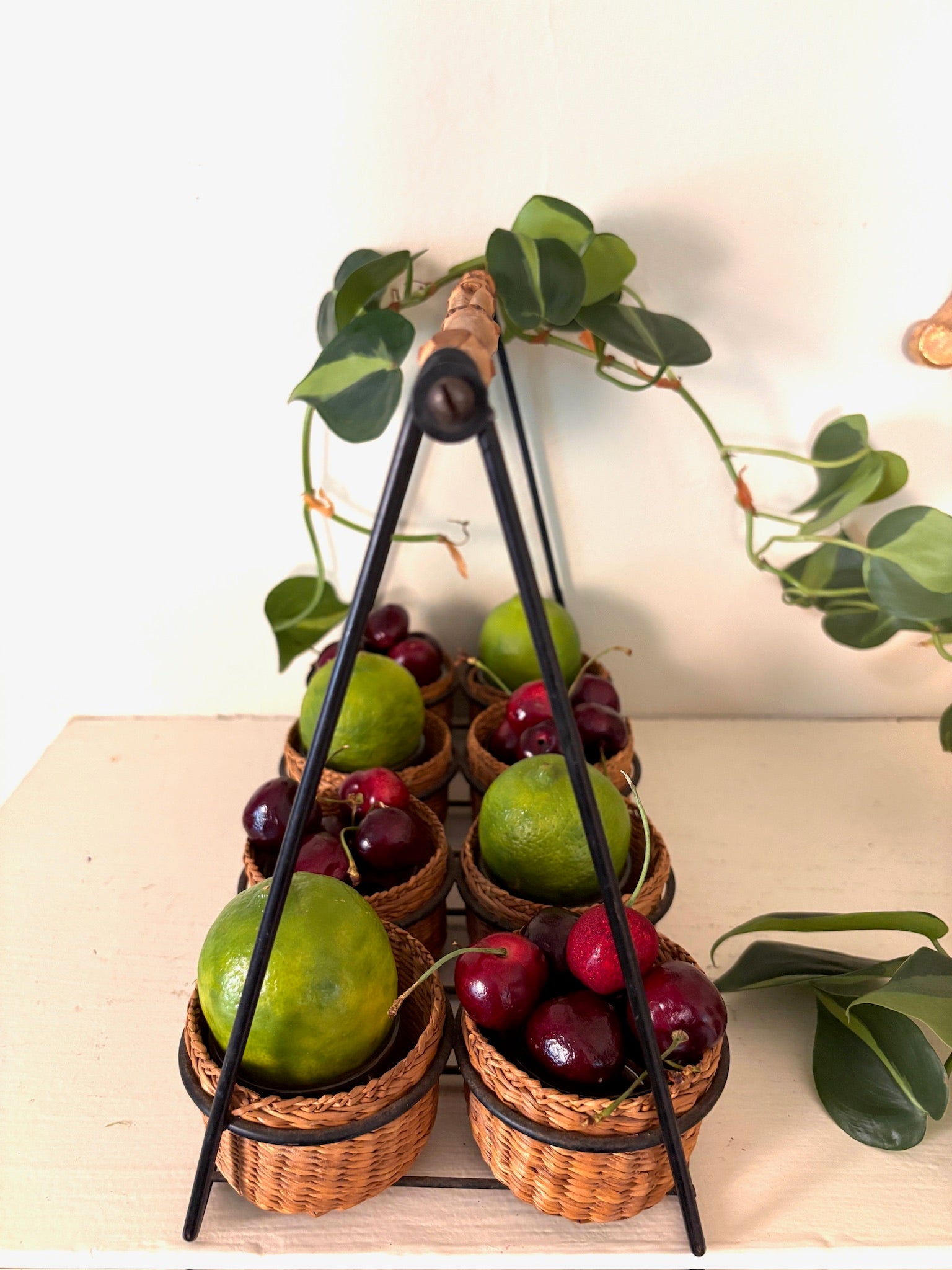 Top view of the rattan basket caddy showing the black A-frame handle meeting at a bamboo-wrapped grip.